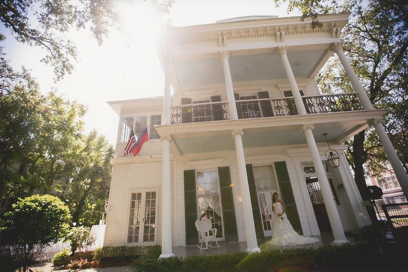 A bride-to-be poses on the front porch of Le Musee.  The picturesque house hosts numerous weddings and other special events throughout the year.