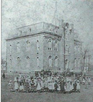 First public school building built after the Civil War. It included all grades up to high school. After construction of a new high school in 1890, this structure became Central School for elementary levels. This image is from an early 1870s stereo view.