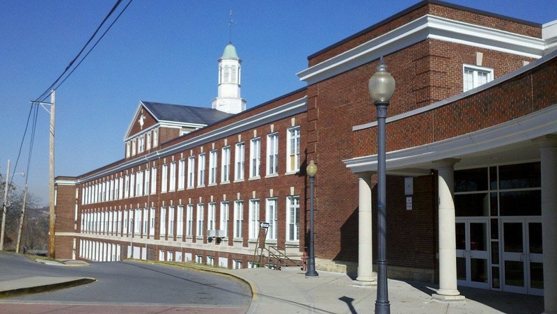 An exterior perspective of the building's main entrance featuring a view of the original structure in the current day.