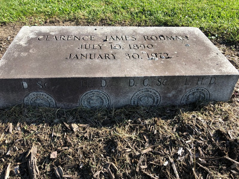 Clarence James Rodman headstone showing University insignias for degrees earned