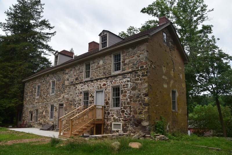 Image of the other side of the same stone house, with a set of wooden steps leading up to the front door.