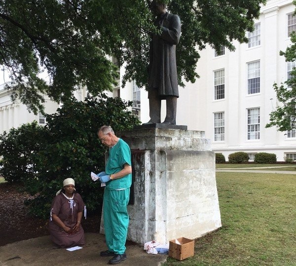 Two protesters portray Dr. Sims performing an operation on an enslaved woman. The physician was arrested by capitol police. Photo from Al.com report which is linked and cited below.