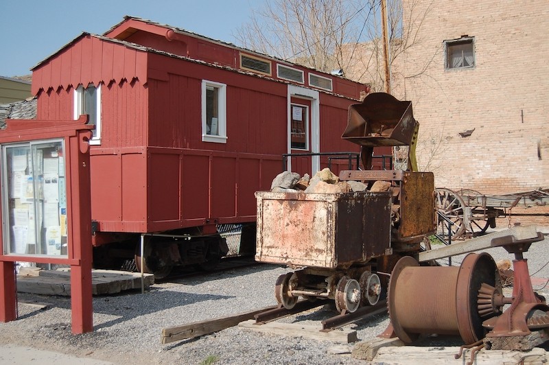 The Eureka and Palisade Railroad car is on display next to historic mining equipment.