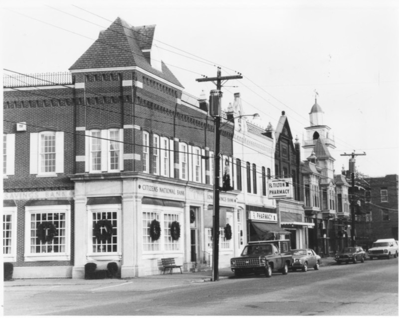 North Side of Main Street incl. Charles E. Tilton Block, Bank Block, Alfred Tilton Block, and the Side of Tilton Block.  Steeple of Northfield-Tilton Congregational Church visible above Alfred Tilton Block by Roger P. Akeley on December 15, 1982