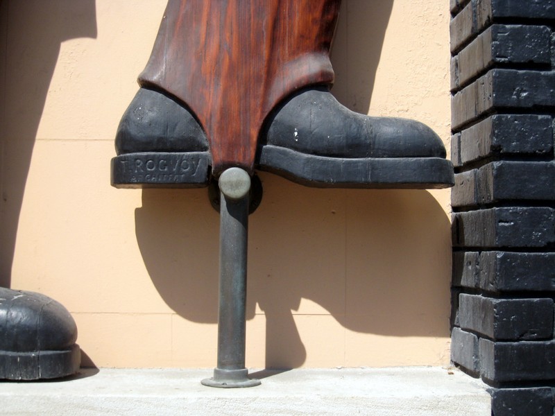 JoachimJungwirth & Co. Brass Rail Woodcarving, left figure boot detail with architect name, 2020