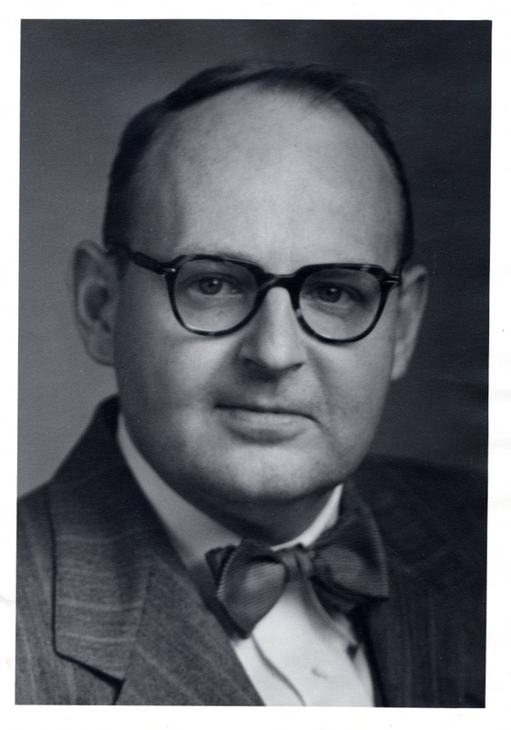 Black and white portrait of Kenneth Swan wearing glasses, a striped blazer, and a bowtie.