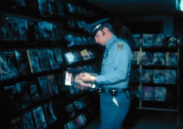 An officer looking at a porn magazine during the 1990 FBI raid of Circus of Books