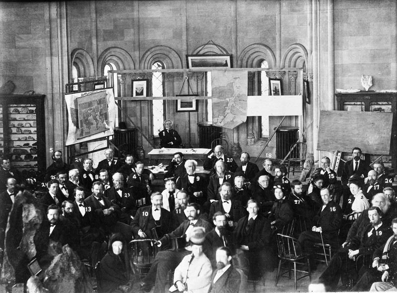 Henry, sitting behind a desk in the back, convenes the National Academy of Sciences in the Castle's Mineral Hall in 1972. Courtesy of the Smithsonian Institution Archives. 