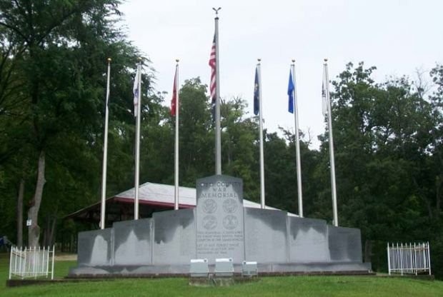 The full granite memorial with the United States flag and the Army, Navy, Marines, and Air Force flags.