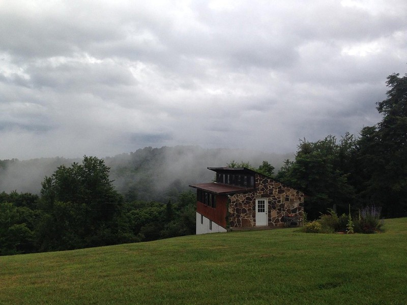 a church type building overlooking a valley in the mountains.