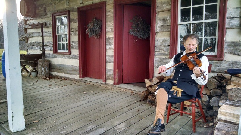 A fiddler enjoys unseasonably warm weather during a Christmas Open House. Annual event the second Saturday of December. Come see the Conococheague Settlement dressed in period decorations. 