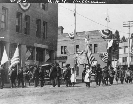 A parade procession heading down Main Street with the Artesian Hotel and the Flatiron Building (middle) in the background. Taken by Artopho Studios in 1912. Courtesy WSU Special Collections. 
http://content.libraries.wsu.edu/cdm/singleitem/collection/pul