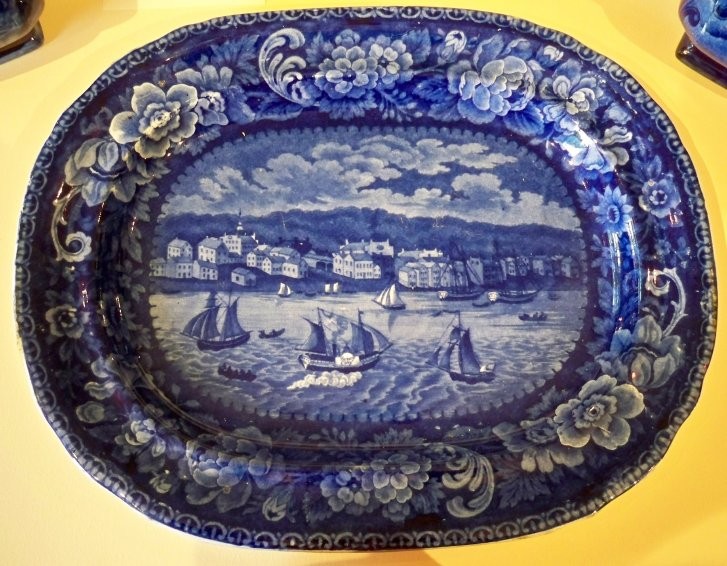 Historical Blue Platter English, mid 19th century. In the "Sandusky" pattern with ship "Henry Clay" in the harbor. Scratches and the table wear to the back. Monor roughness on the rim.  The small building at the extreme east was the first building where ice cream was sold in the city. Next to the north was Doll's Hotel with a dance hall in the upper story. The building with a spire was the Episcopal church for which the cornerstone was laid in 1835 and Wm. T. West and his wife were the first couple married in the church in 1844. Between the church and Doll's Hotel was Charles Rice's wagon shop. The large building with the sheds was the Steamboat Hotel, later called the Verandah, at the foot of Wayne Street, which was raised in 1923. East of it was a boarding house kept by the Widow Hurd. To the southwest of the Steamboat Hotel was the first stone house in Sandusky, built by Eleutheros Cooke, where the Star Theatre now stands. The building west of the Cooke residence are the Methodist and Congregational churches. West of the Steamboat Hotel on Water Street was William Boos' Bakery. then came a boarding house. Then to the west, the residence of Captain Ransome and the larger four story building was the Ohio House. The third building from the westside of the picture was William Townsend's store. The rest of the buildings were mostly log cabins. The Henry Clay was built in 1838. The picture does not show Colt's Exchange Hotel, which shows the picture was prior to April 1842, when Charles Dickens visited the city.