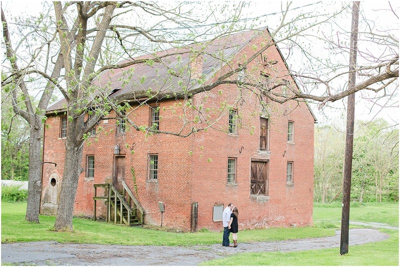 A happy couple celebrates their engagement in front of the grist mill.