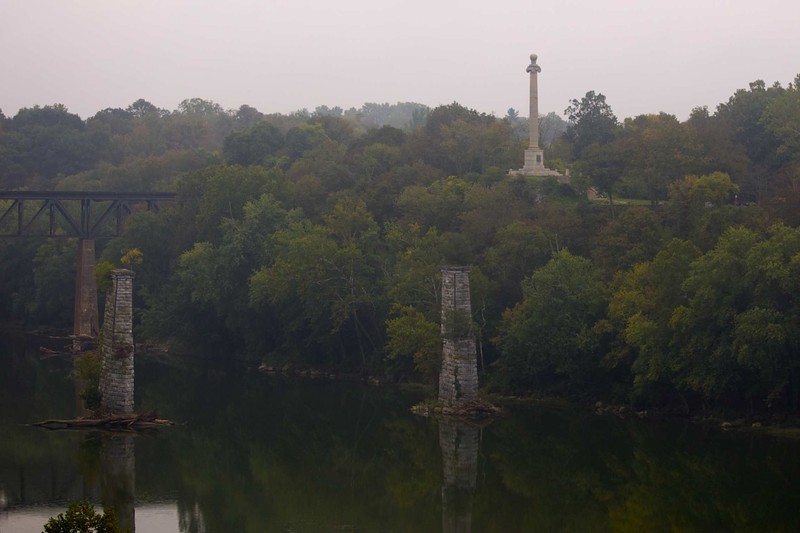 Depicted here is the monument (the white pillar in the upper right corner) overlooking the Potomac River. The bridge displayed is a railroad connected to Maryland.

From the Rumsian Society: https://jamesrumsey.org/the-rumsey-monument/
