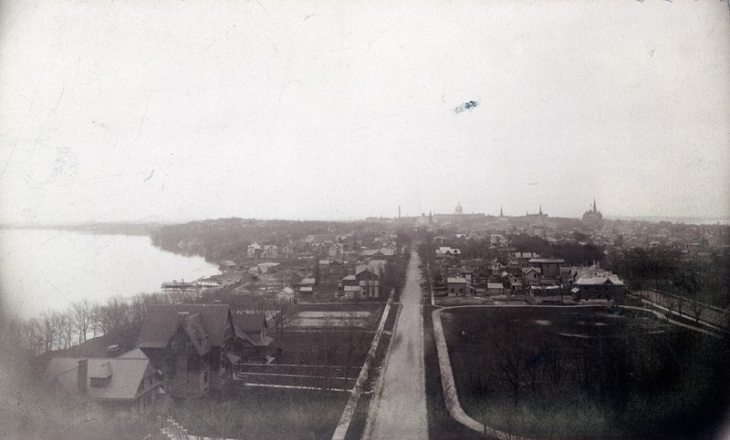 A cabinet card photograph of the skyline of Madison, Wisconsin from around 1890 taken from the western end of Langdon Street. The three houses in the lower left of the photograph sit on the lot that would later become Memorial Union. Also visible is the lot that would become the Red Gym. 