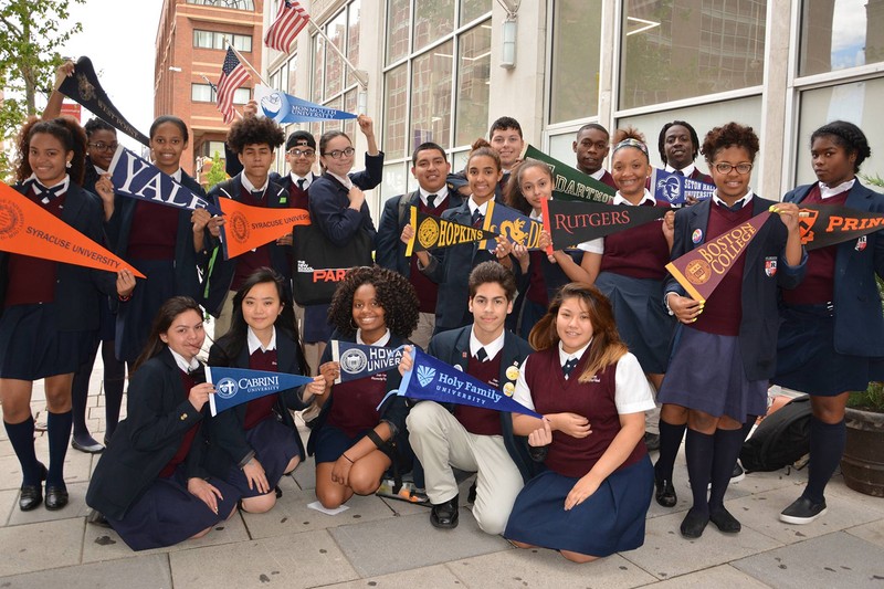 LEAP Academy graduates holding flags of the various instituations they were accepted to