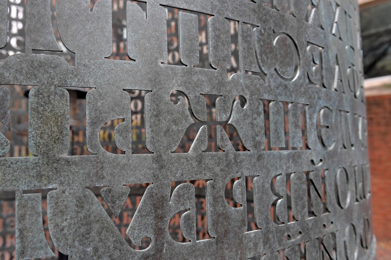 Close up image of bronze sculpture with Cyrillic letters cut out of the surface