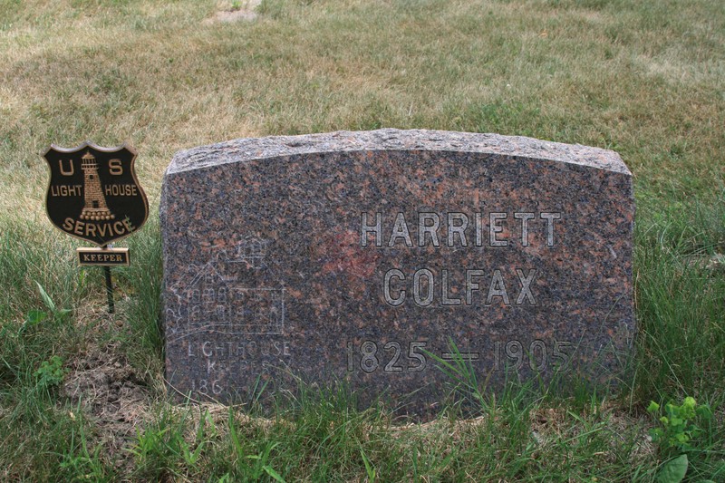 A granite marker with the name "Harriet Colfax" and a picture of a lighthouse carved on the face.