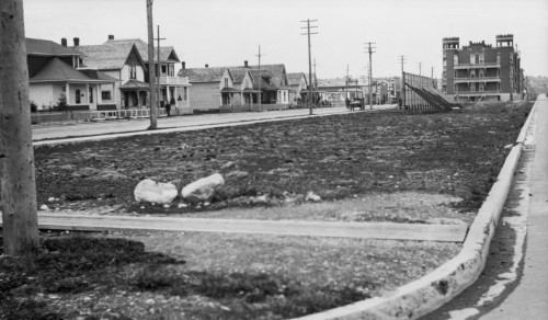 Black and white image of empty park with buildings in the background