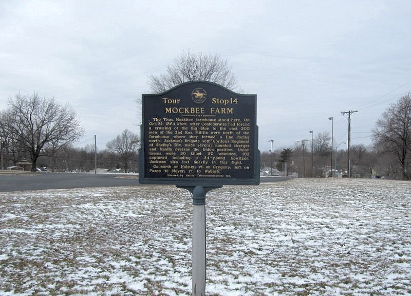 Historical marker with the background covered in snow. Historical Marker Inscription: The Thos. Mockbee farmhouse stood here. On Oct. 22, 1864 when after Confederates had forced a crossing of the Big Blue to the east 300 men of the 2nd Kas. Militia were north of the farmhouse where they formed a line facing north. Jackman’s Brigade with Gordon’s Regiment of Shelby’s Div. made several mounted charges and finally overran the union Position. Union losses were 30 killed, 50 wounded, 102 captured including a 24-pound howitzer. Jackman also lost heavily in this fight.
