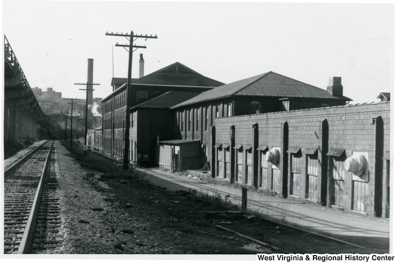 View of the east side of building along the railroad (now the Rail Trail) looking south. This image from the late 1980s depicts the original textile building as well as some additions. West Virginia and Regional History Center, WVU Libraries.