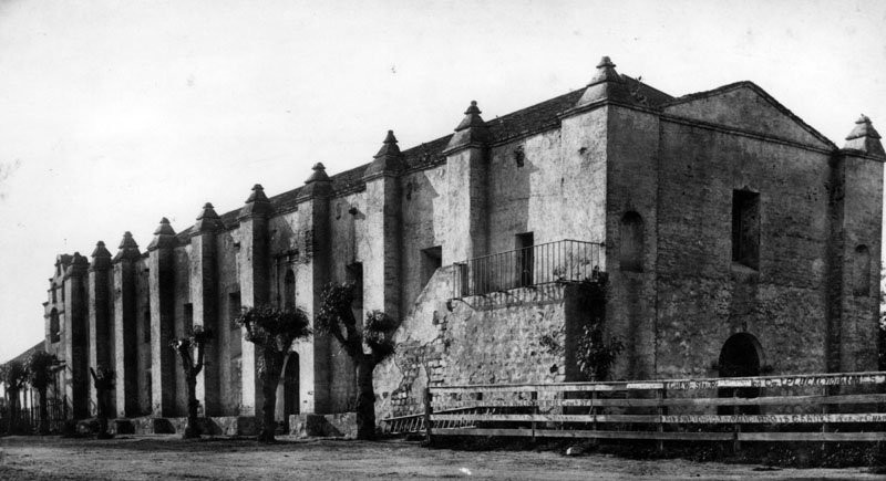 West end and southern facade in the late 1800s. The writing on the wooden fence in foreground are handwritten advertisements from local merchants. Courtesy of Water and Power Associates.