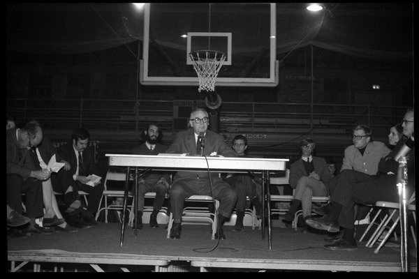 Drucker, Jeffrey (photographer). Oswald Tippo (Provost, UMass Amherst) speaks at open meeting with school administration, Curry Hicks Cage, regarding protests against war in Vietnam, ca. February 19, 1968. 
From a series of images of the mass studen