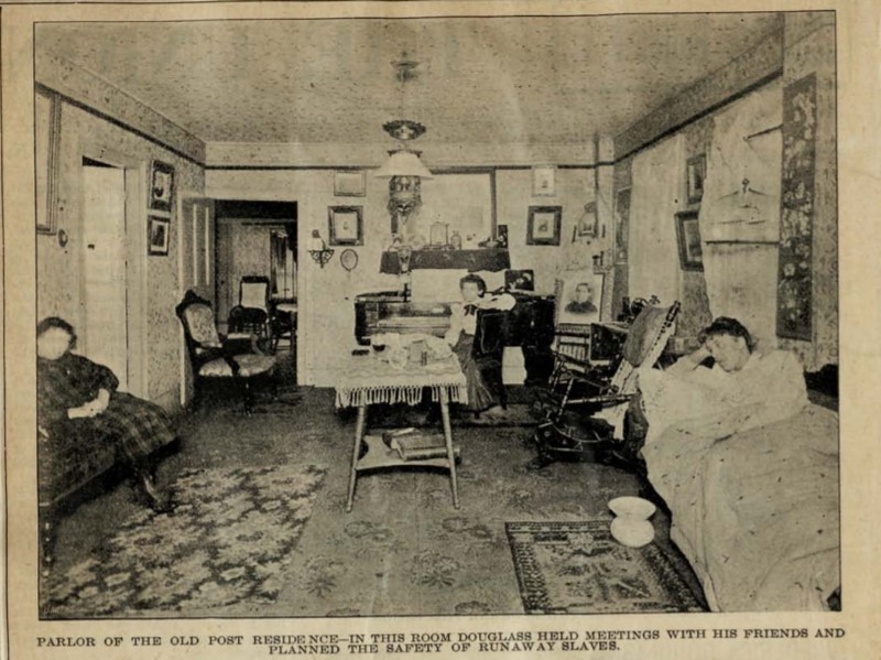 This undated photograph is of the parlor in the old Post Residence. The figures are unidentified. The image of the parlor is captioned, "In this room Douglass held meetings with his friends and planned the safety of runaway slaves."