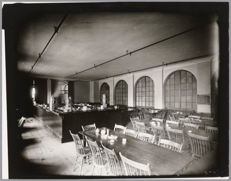 Banquet tables in foreground and a buffet in the rear. Arched windows line the wall.
