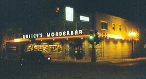 Night view of restaurant and "Whitey's Wonderbar" sign lit with neon lighting.