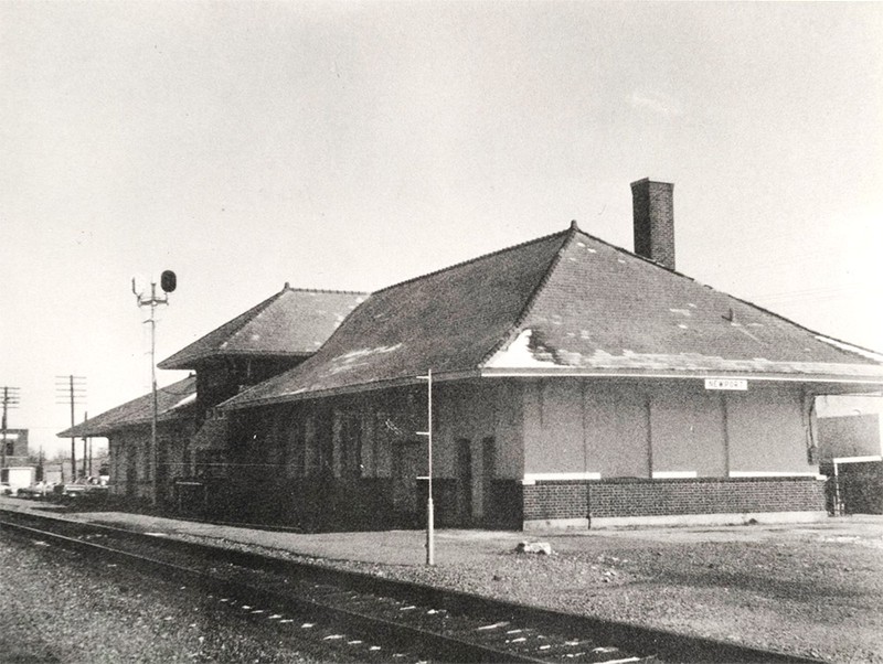 A black of white photo of a building and railroad tracks.