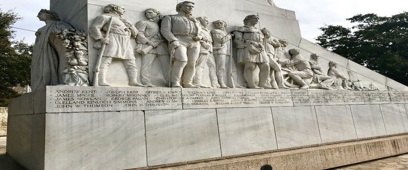 Side angle of Travis, Crockett, the eight soldiers, and the inscribed names of the fallen heroes. 