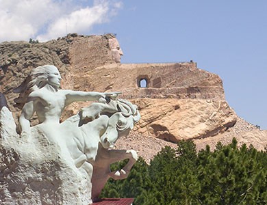 This photo shows a model of the sculpture in the foreground and the current state of the massive monument in the background. 