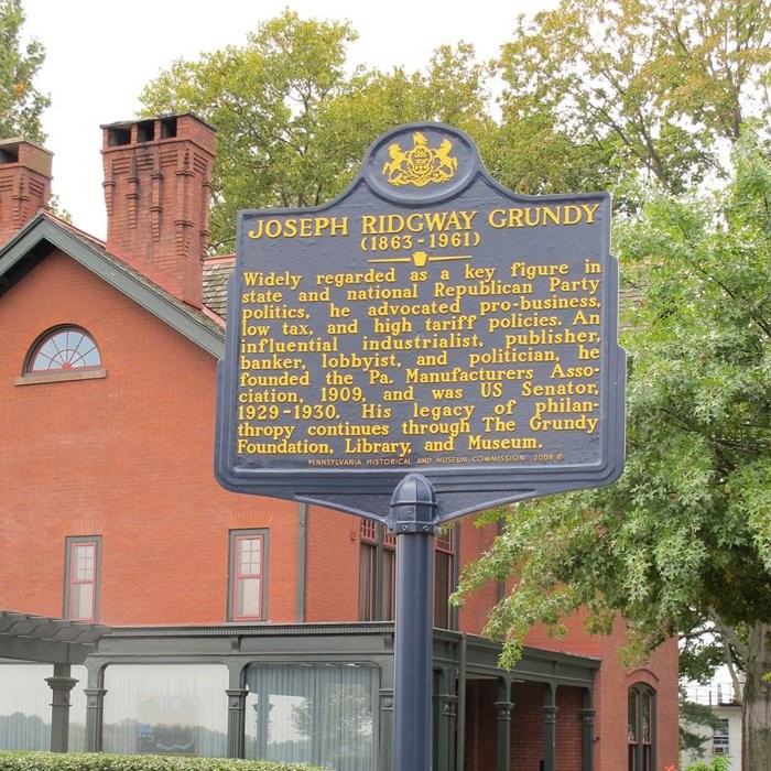 The historical marker dedicated to Joseph Grundy with his former home in the background.  