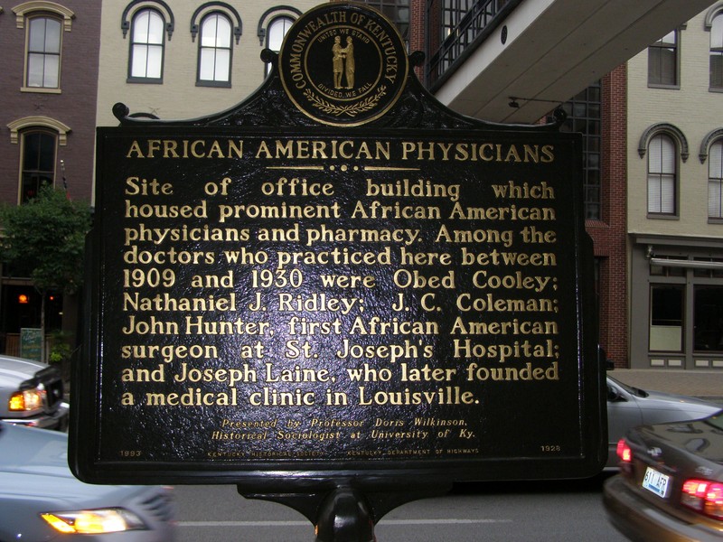 This is the front of the African American Physicians marker. It states that it is the site of the building that housed prominent African-American physicians and pharmacy. This marker provides information about specific doctors.