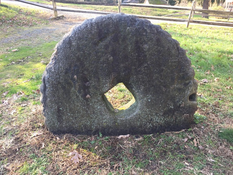 Image of a millstone set on its side into the ground.