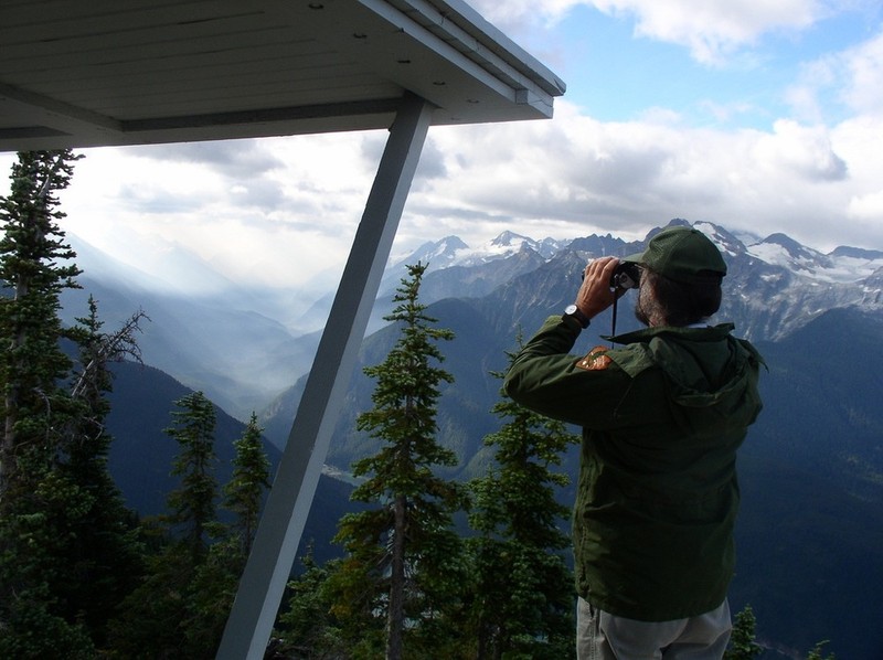 A park ranger looks through his binoculars from Sourdough Lookout.