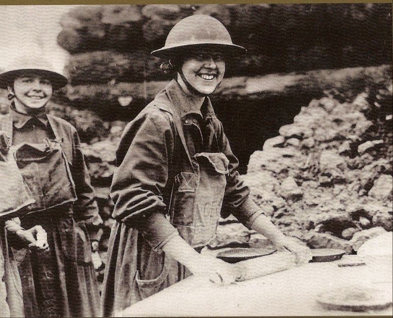 An image of two women wearing a modified WW1 military uniform while making food for soldiers.