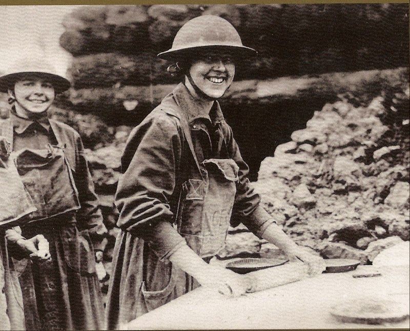 An image of two women wearing a modified WW1 military uniform while making food for soldiers. 