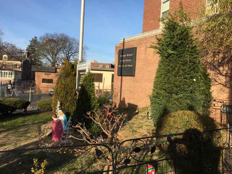 Front lawn of church decorated with Christmas lights and ornaments; off to the left a man selling Mexican sweet bread (pan dulce mexicano) from a carrito