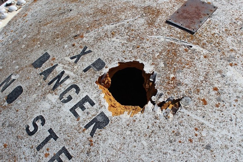 Closeup of a broken cover.  There is a second cover about three feet down.