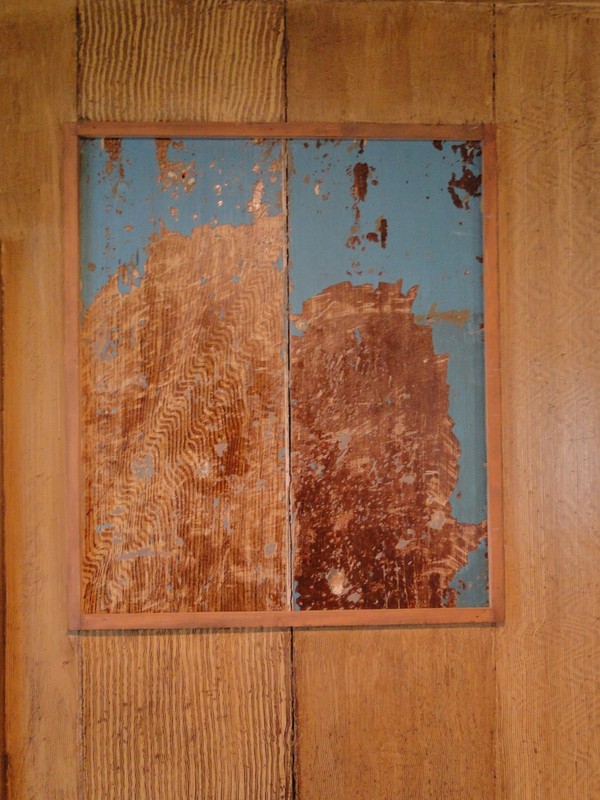 Wood graining is the process of painting something to look like wood. The framed area shows original wood graining on a first floor wall done by the Netzley family in the 1800s. The area outside of the frame was painted by volunteers during museum restoration.