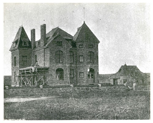 Black and white image of sandstone mansion under construction