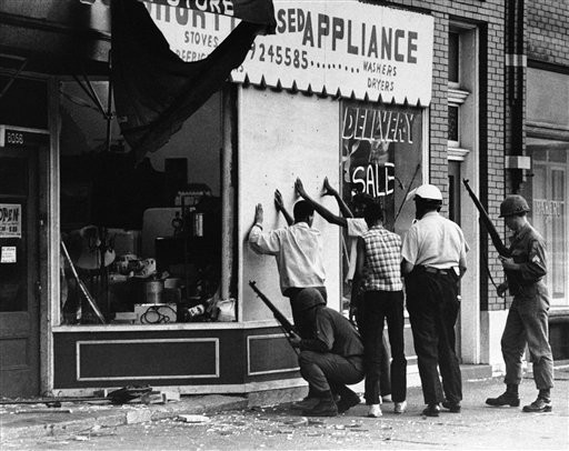 Policemen and National Guardsman search three youths they found wandering down a Detroit street in an East Sde area hit by rioting, July 25, 1967. Many fires were set and sniping and looting was rampant.