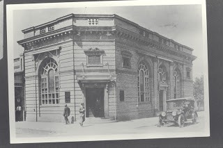 Full image of the historic Bank of Shasta County (1920) showing pedestrians and an automobile on the street
