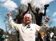 Johnny Kelley in front of the statue at the base of Heartbreak Hill