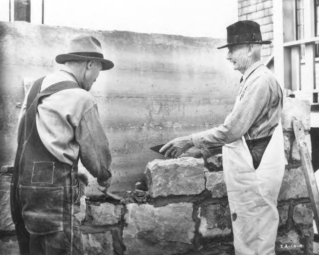 B&W photo of two stone masons laying numbered stones in place for rebuilding of dismantled church on new site.  For Lee Merrill Advertising. For over half a century, St. Luke's had stood at the corner of 6th and Broadway. The historic church was being dismantled brick by brick and being rebuilt at No. 36th & Gove Streets, formerly the location of St. Mark's. St. Mark's became the new St. Luke's as construction proceeded and was moved to 3615 No. Gove in 1937 to make room for the rebuilt structure. (WSHS)