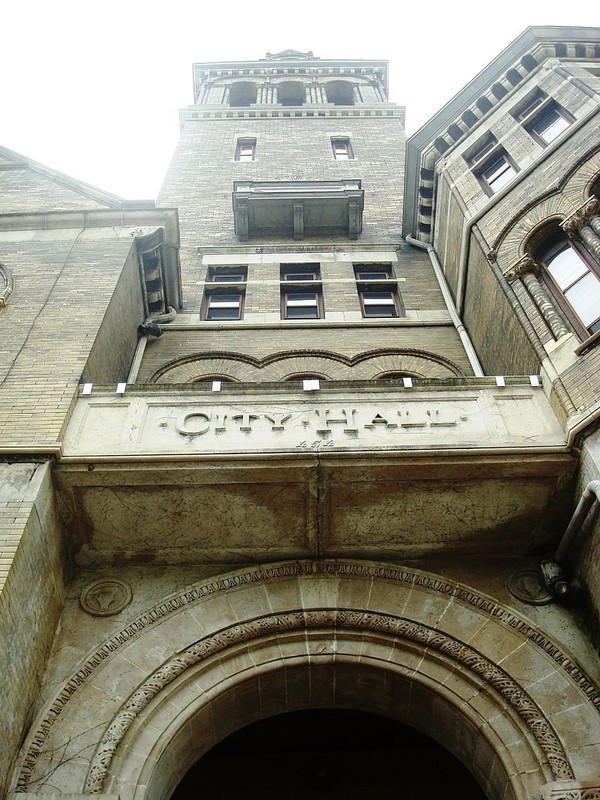 Standing on the steps at the building's entrance, looking up at its six-story central tower.