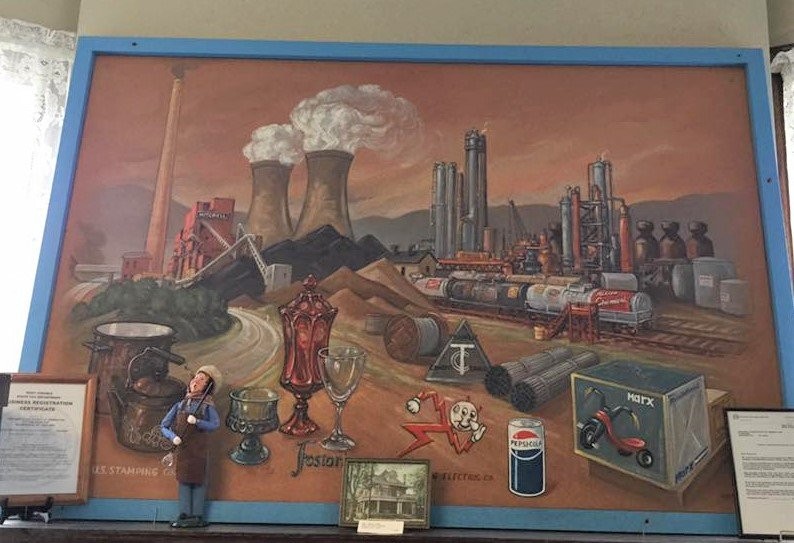 Local residents might recognize this picture that once hung in a local bank. It represents the many industries once present in Marshall County. Now the painting hangs in the main entrance to the Fostoria Glass Museum.